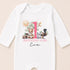 A white onesie with a pink number 1 and various animal illustrations, along with the text "BIRTHDAY GIRL Eva".