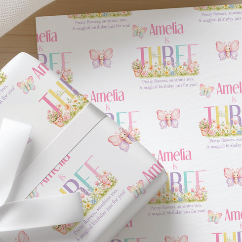a repeating pattern of a white background with the name "Amelia" and the phrase "A magical birthday just for you!" written in pink and purple. The pattern is composed of multiple images of butterflies and flowers, creating a visually appealing and personalized design.