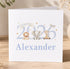 A white greeting card with a design featuring a lion, an elephant, and a giraffe, along with the text "Born in 2026 Alexander".
