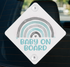 A white diamond-shaped sign with a rainbow graphic and the text "BABY ON BOARD" printed on it.