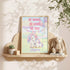 a framed poster with a unicorn and a bunny, along with a motivational message, placed on a shelf next to a stuffed animal.