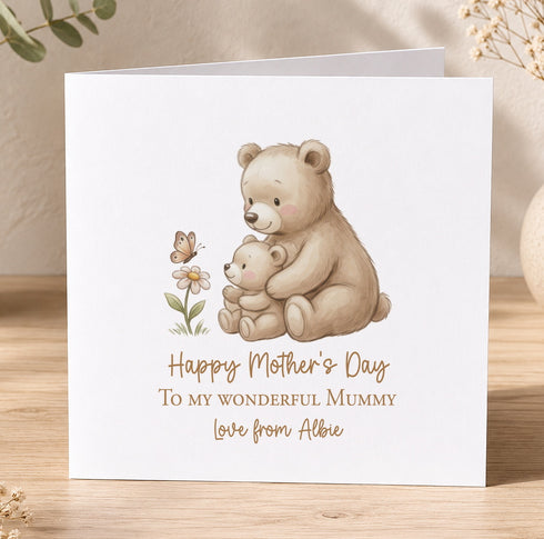 A greeting card with an illustration of two bears, one larger and one smaller, sitting together and holding a flower. The card has a message that reads "Happy Mother's Day To my wonderful mummy Love from Albie".