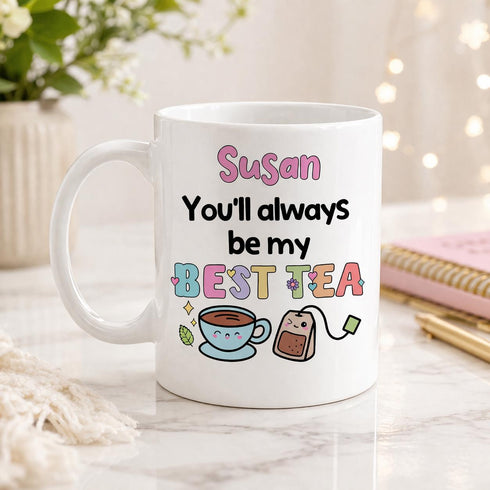 A white mug with a colorful design and text on it, placed on a marble surface.