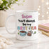 A white mug with a colorful design and text on it, placed on a marble surface.