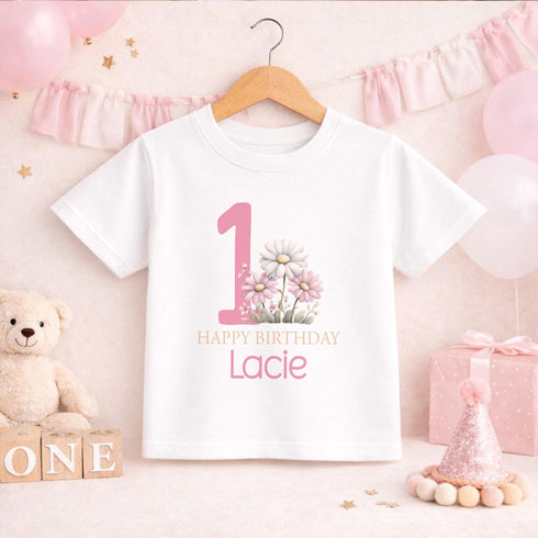 Personalised 1st birthday girl outfit with pink number 1, pretty daisy flower design, happy birthday text and custom name, shown on bib, vest, t-shirt, pyjamas and sleepsuit.