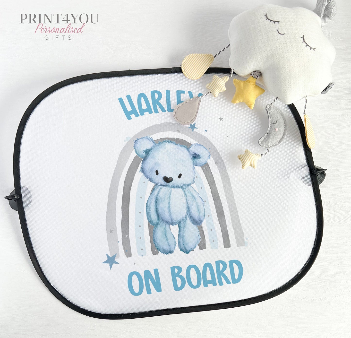 Personalised car sun shade with a blue rainbow and teddy bear design and baby on board wording