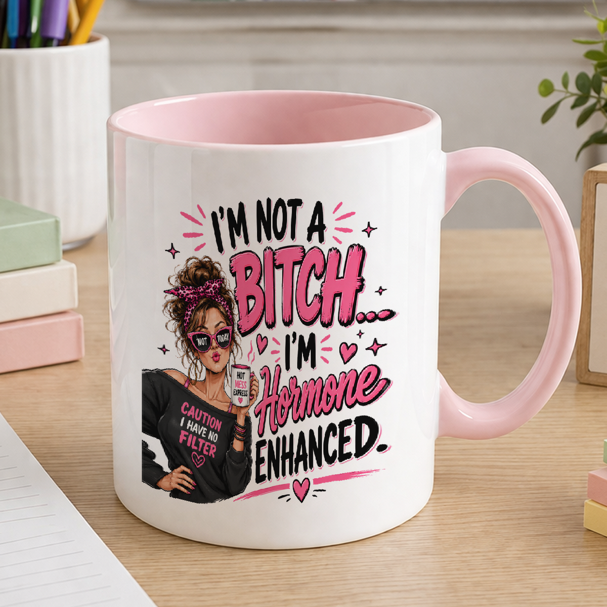 White ceramic mug with pink handle and pink inner, printed with an illustrated woman in sunglasses and the text I'm not a bitch, I'm hormone enhanced