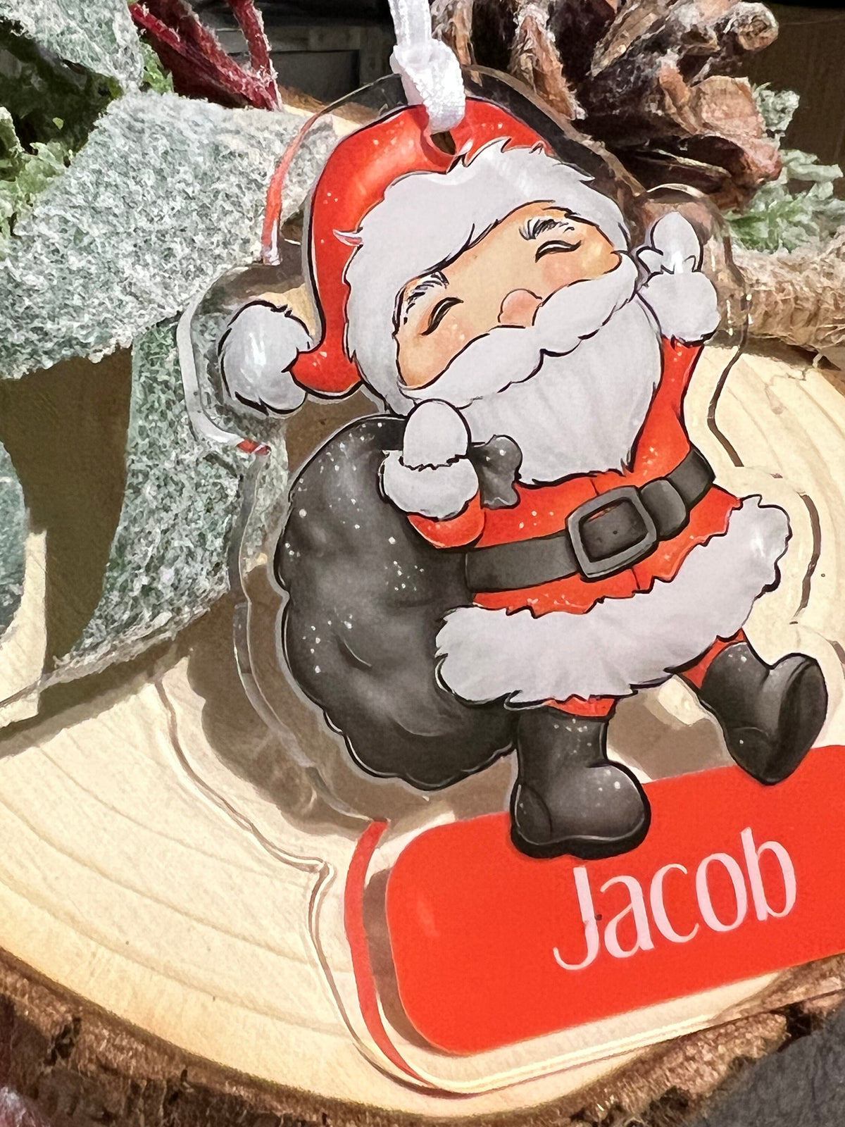 Close-up of personalised acrylic Father Christmas Santa Claus tree bauble showing the custom name printed on the front