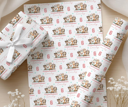 Sheets of personalised wrapping paper printed with elephants and giraffes and the custom name Emilly, displayed on a wooden surface with white flowers