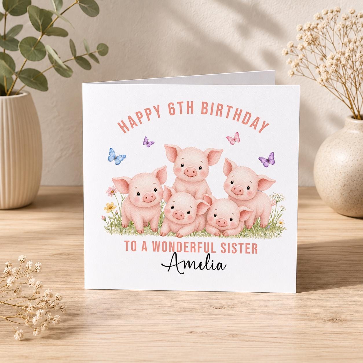 Square birthday card with five pink piglets in a flower field surrounded by butterflies, personalised Happy 6th Birthday to a Wonderful Sister Amelia.