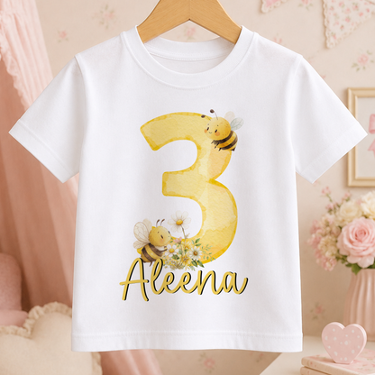 A white t-shirt with a yellow number 3 and a bee design, along with the name "Alena" printed below it.