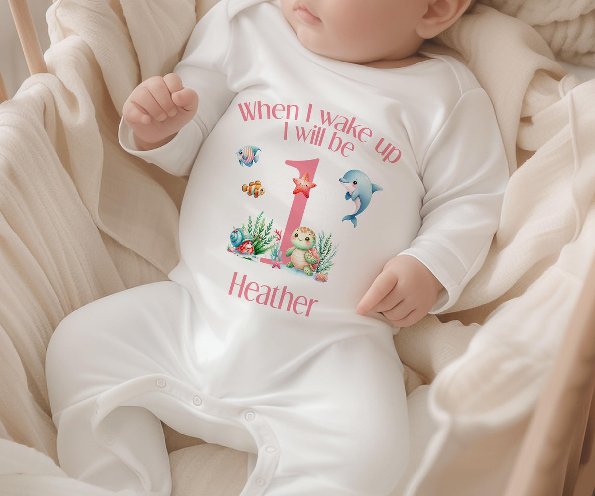 Pink striped baby garment with swimming sea creatures printed alongside a personalised name