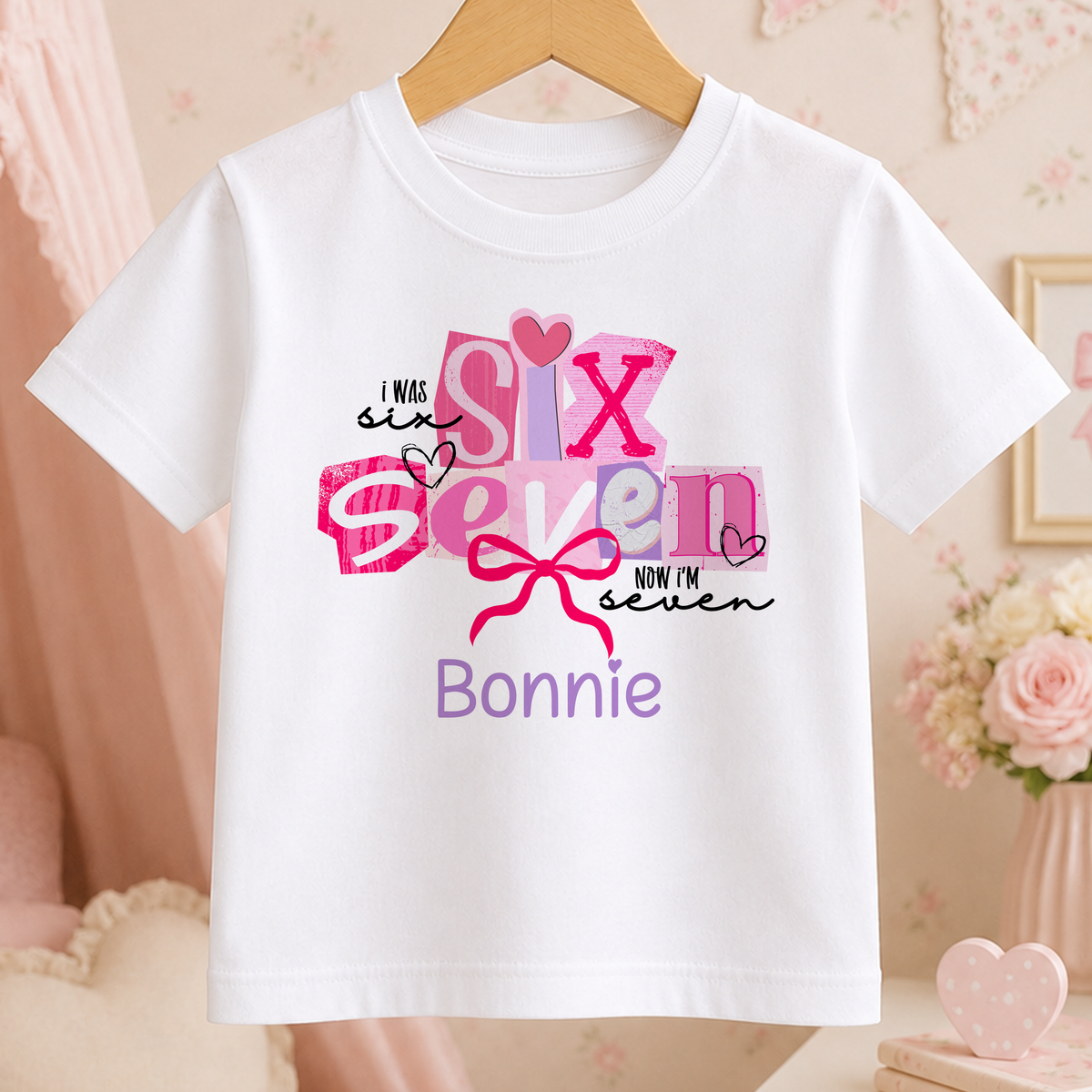 A white t-shirt with a pink and purple design that says "I WAS SIX SEVEN NOW I'M BONNIE" printed on it.