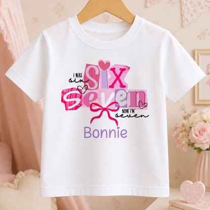 A white t-shirt with a pink and purple design that says "I WAS SIX SEVEN NOW I'M BONNIE" printed on it.