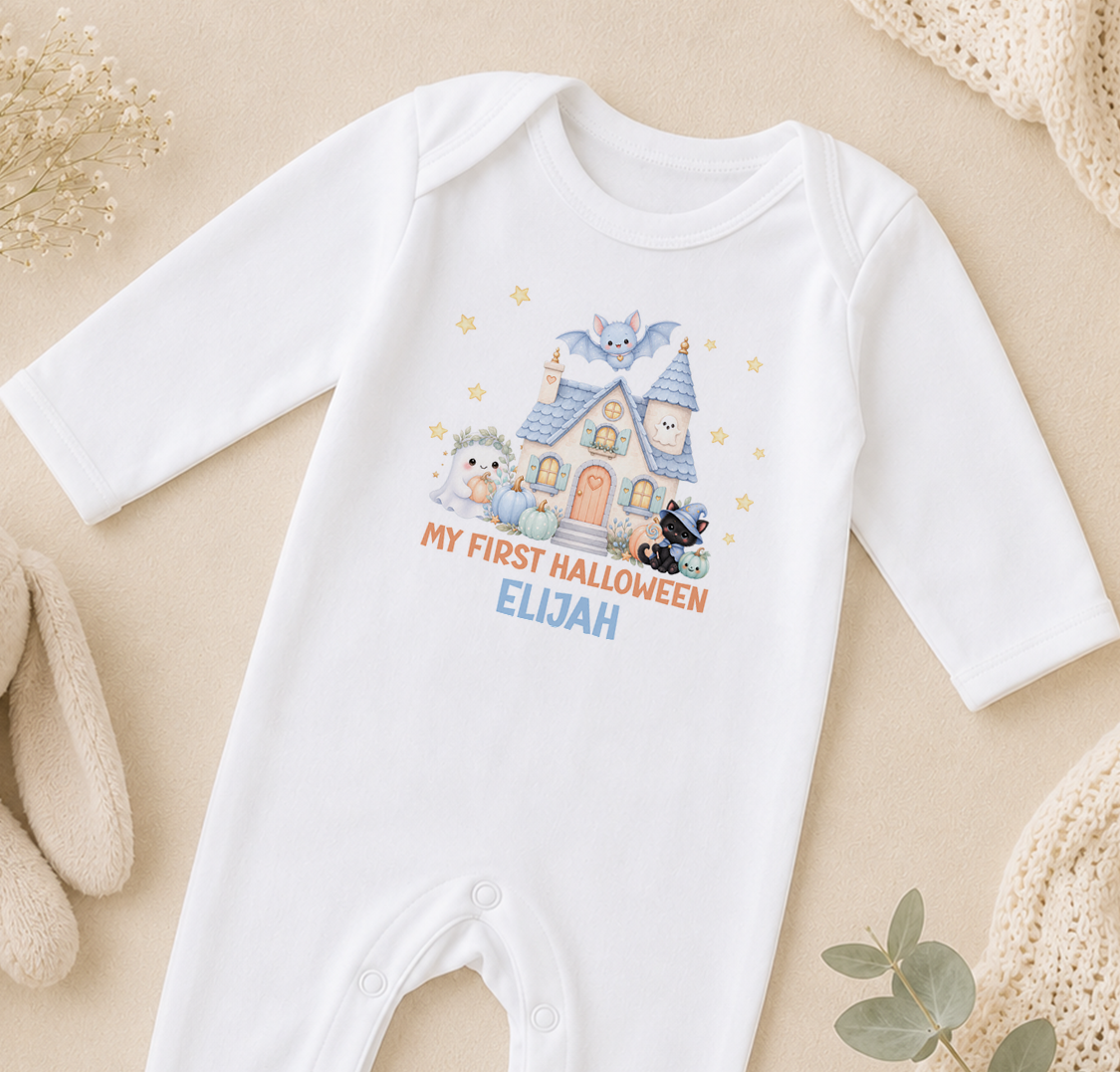 A white onesie with a Halloween-themed design, including a house, bats, and a teddy bear, along with the text "My first Halloween Elijah".