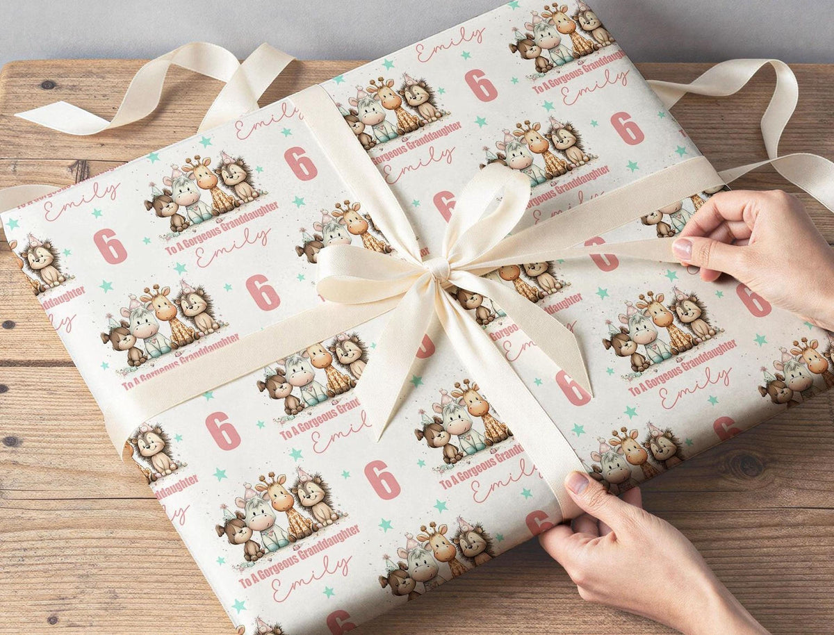 Close-up of hands wrapping a birthday present in the personalised animal wrapping paper, printed with To A Girl Emily