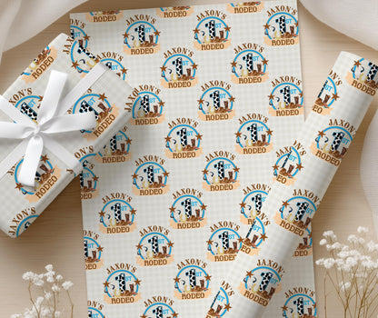 Cowboy-themed rodeo wrapping paper with repeated 'RODEO' text, finished with a white ribbon on a wooden surface.