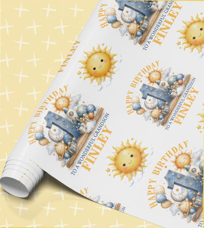 Personalised 1st birthday wrapping paper roll with smiling sun, moon and rocket design and the name Finley