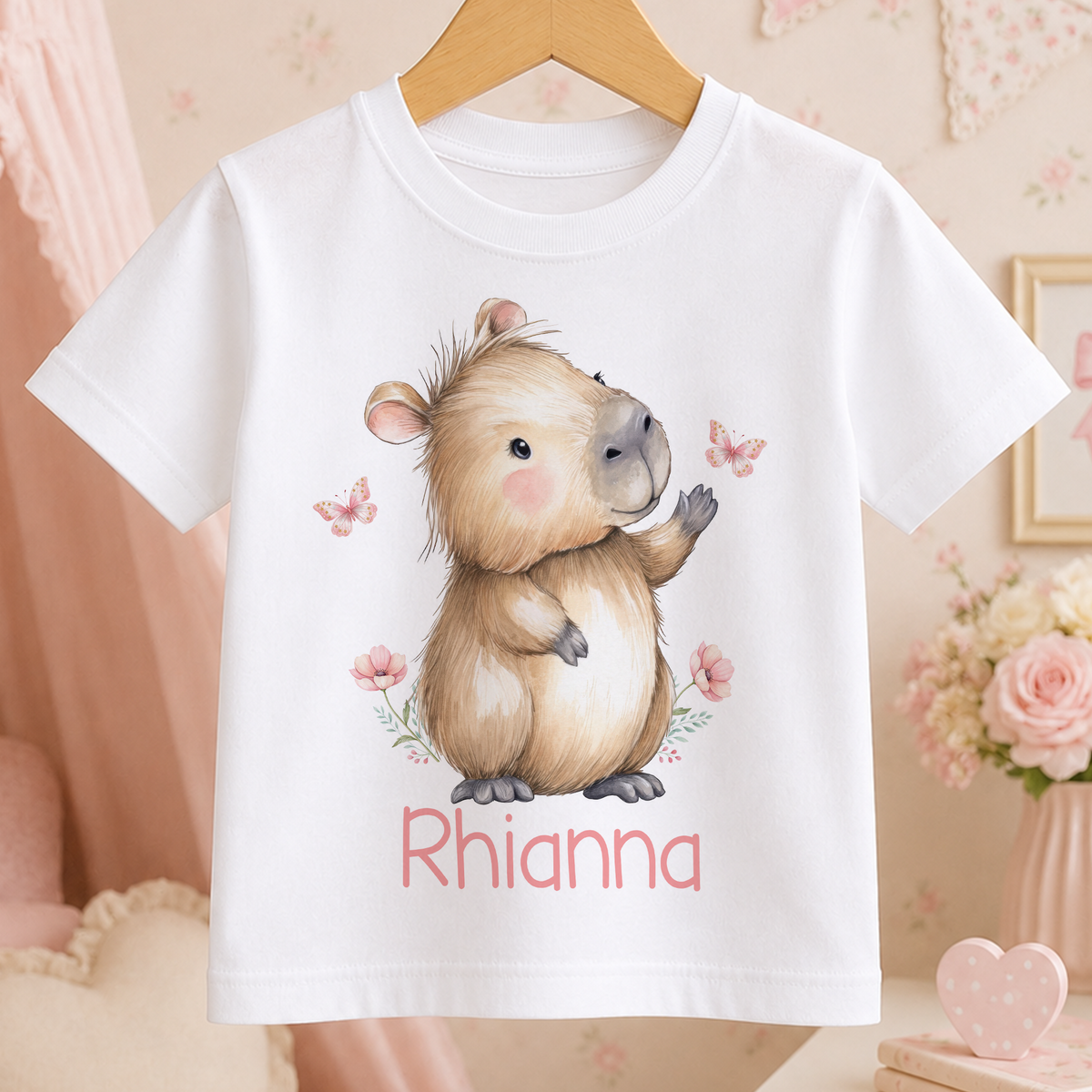 A white t-shirt with a cartoon image of a cute brown animal, possibly a rodent or a small mammal, and the name "Rhianna" printed on it.