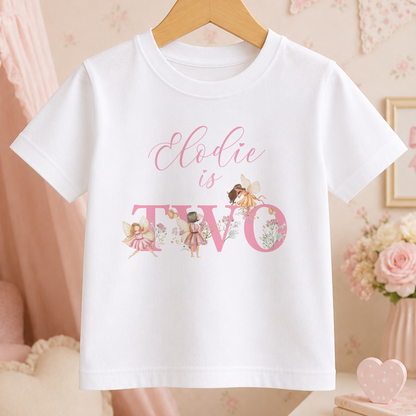 A white t-shirt with a personalized text and illustrations printed on it, hanging on a wooden hanger.