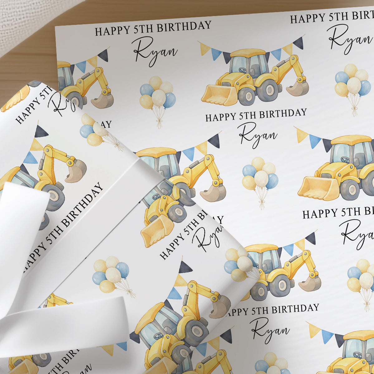 Repeating pattern of yellow diggers and construction vehicles on personalised birthday wrapping paper