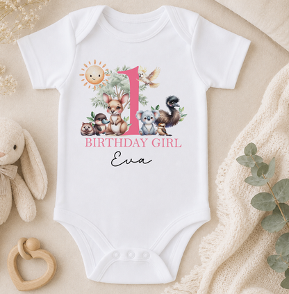 A white onesie with a pink number one and various animal illustrations, including a rabbit, kangaroo, and koala, along with the text "BIRTHDAY GIRL Eva".
