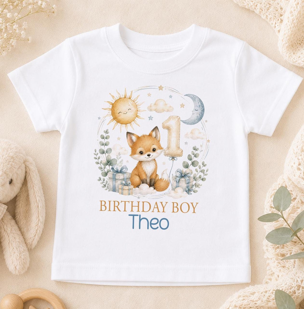 White cotton t-shirt printed with a watercolour fox cub, sun, moon and a number one balloon, with Birthday Boy and a name below.