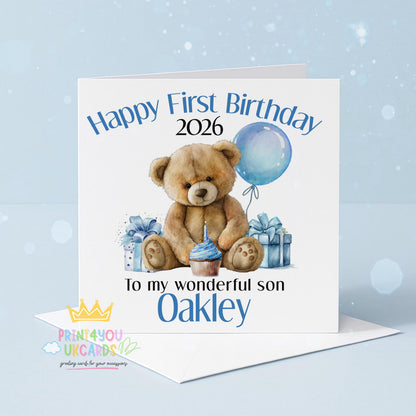 Square first birthday greeting card shown at an angle to display the blue teddy bear design and card stock.