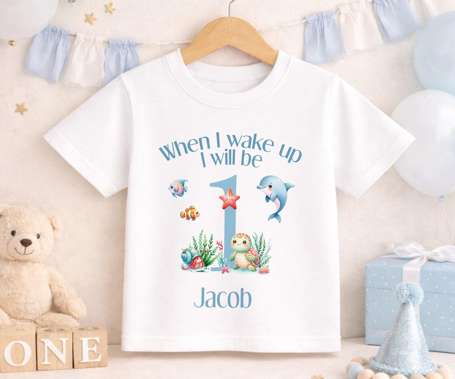Personalised under-the-sea first birthday outfit laid flat to show the full printed design.