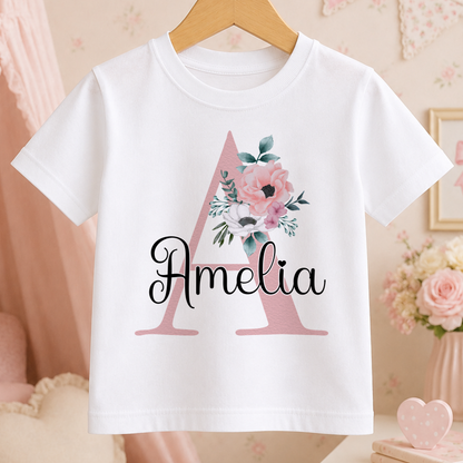 A white t-shirt with a pink floral design and the name "Amelia" printed on it.
