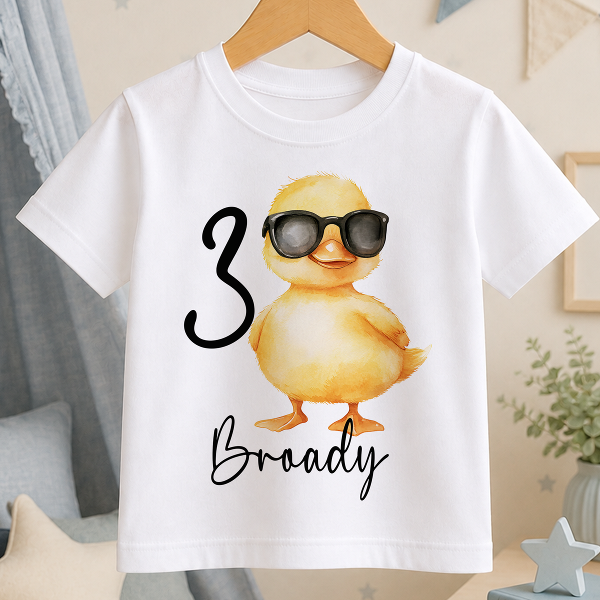 A white t-shirt with a cartoon image of a duck wearing sunglasses and the number "3" printed on it.