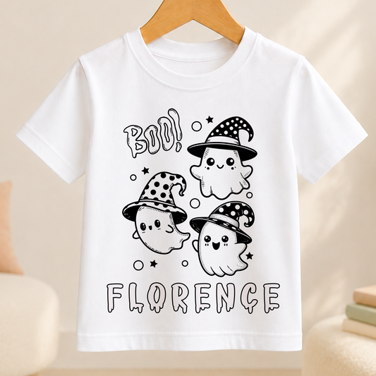 A white t-shirt with a graphic design featuring three cartoon ghost characters wearing hats and surrounded by stars. The text "BOO!" is written above the ghost characters, and the name "FLORENCE" is written below them.