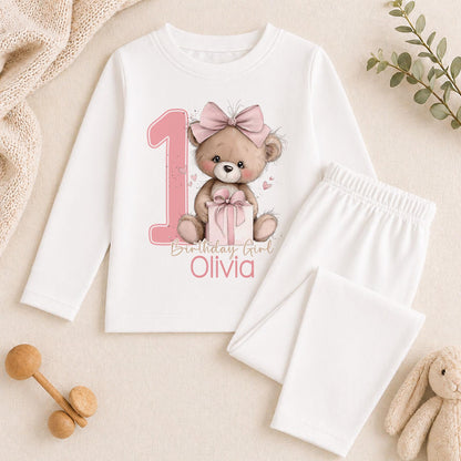 Personalised pink teddy bear first birthday outfit shown with a sample name printed on soft cotton.