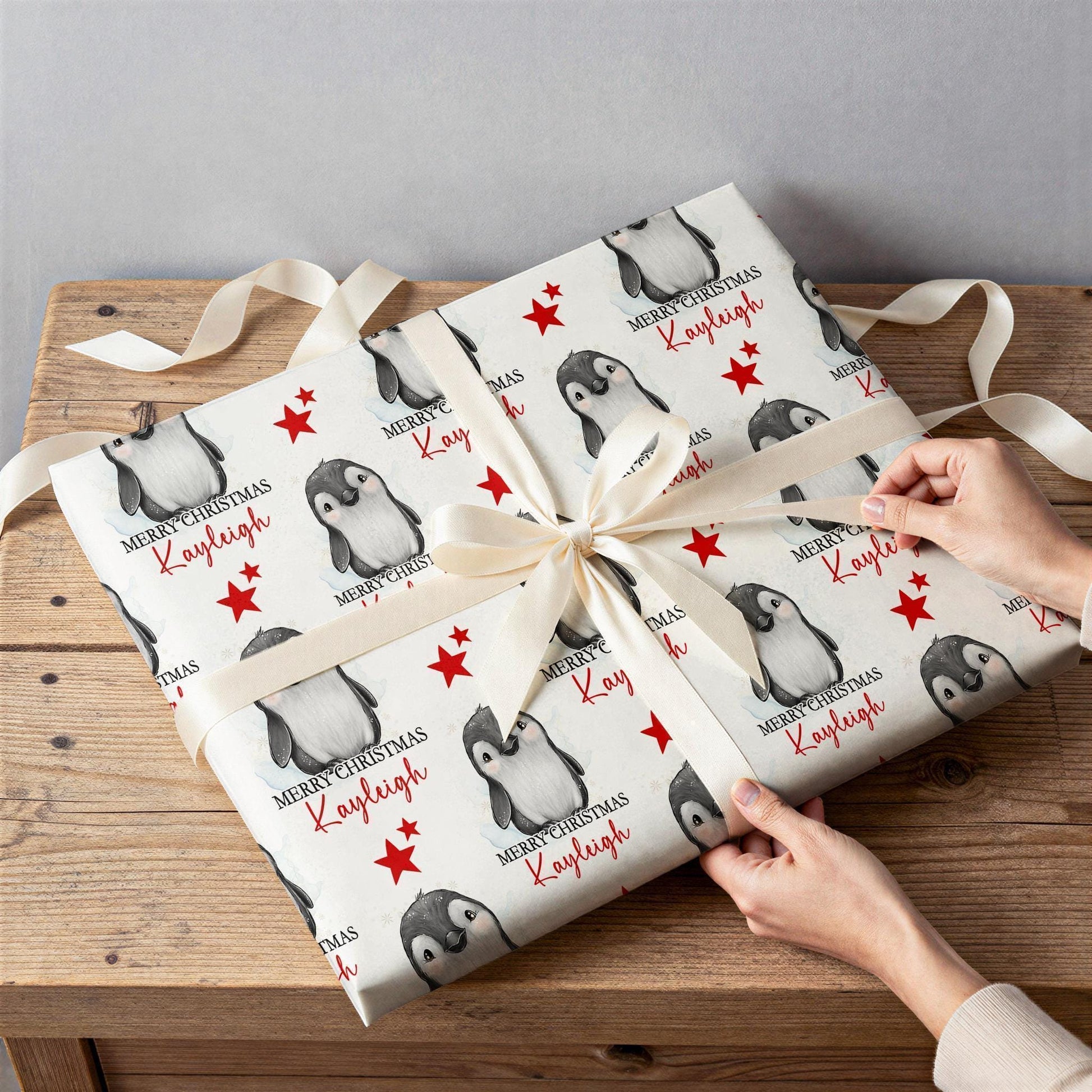 Close-up detail of the personalised penguin and red star Christmas wrapping paper design