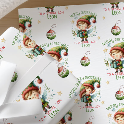 Close-up of personalised Christmas wrapping paper featuring a cute festive elf with Christmas baubles and a repeating holiday pattern on premium white gift wrap