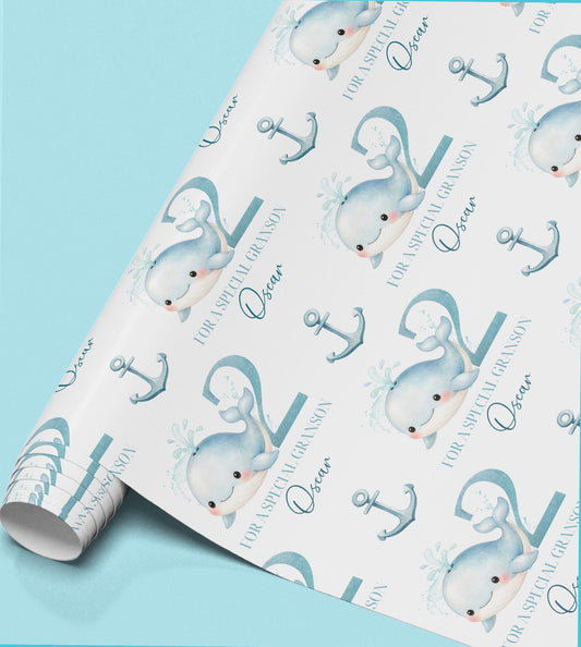 Roll of personalised boys' wrapping paper featuring a repeating pastel blue whale and anchor design.