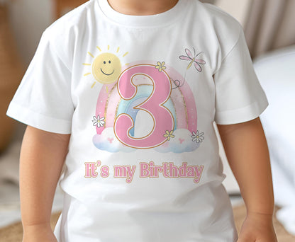 Baby girl wearing a white cotton birthday t-shirt printed with a daisy and rainbow design, size 6-12 months