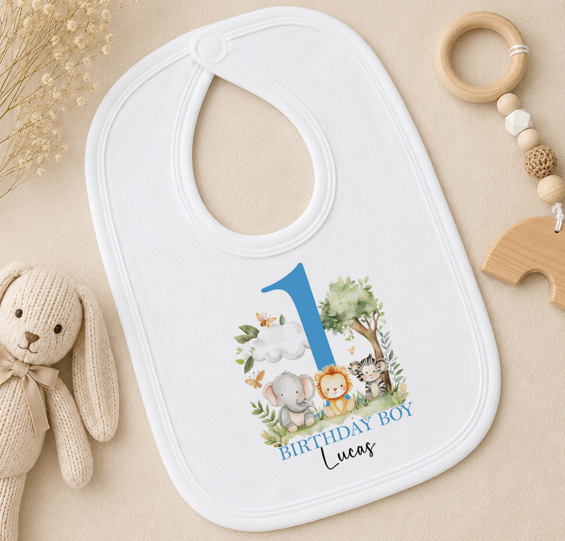 A white baby bib with a blue number 1 and a design of animals, including a rabbit, elephant, lion, and tiger, along with the text "BIRTHDAY BOY Lucas".