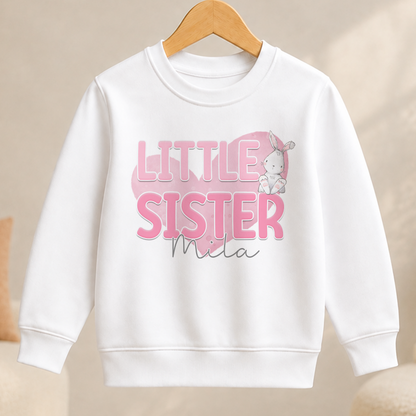 A white children's sweatshirt with the text "LITTLE SISTER" and a small illustration of a rabbit.