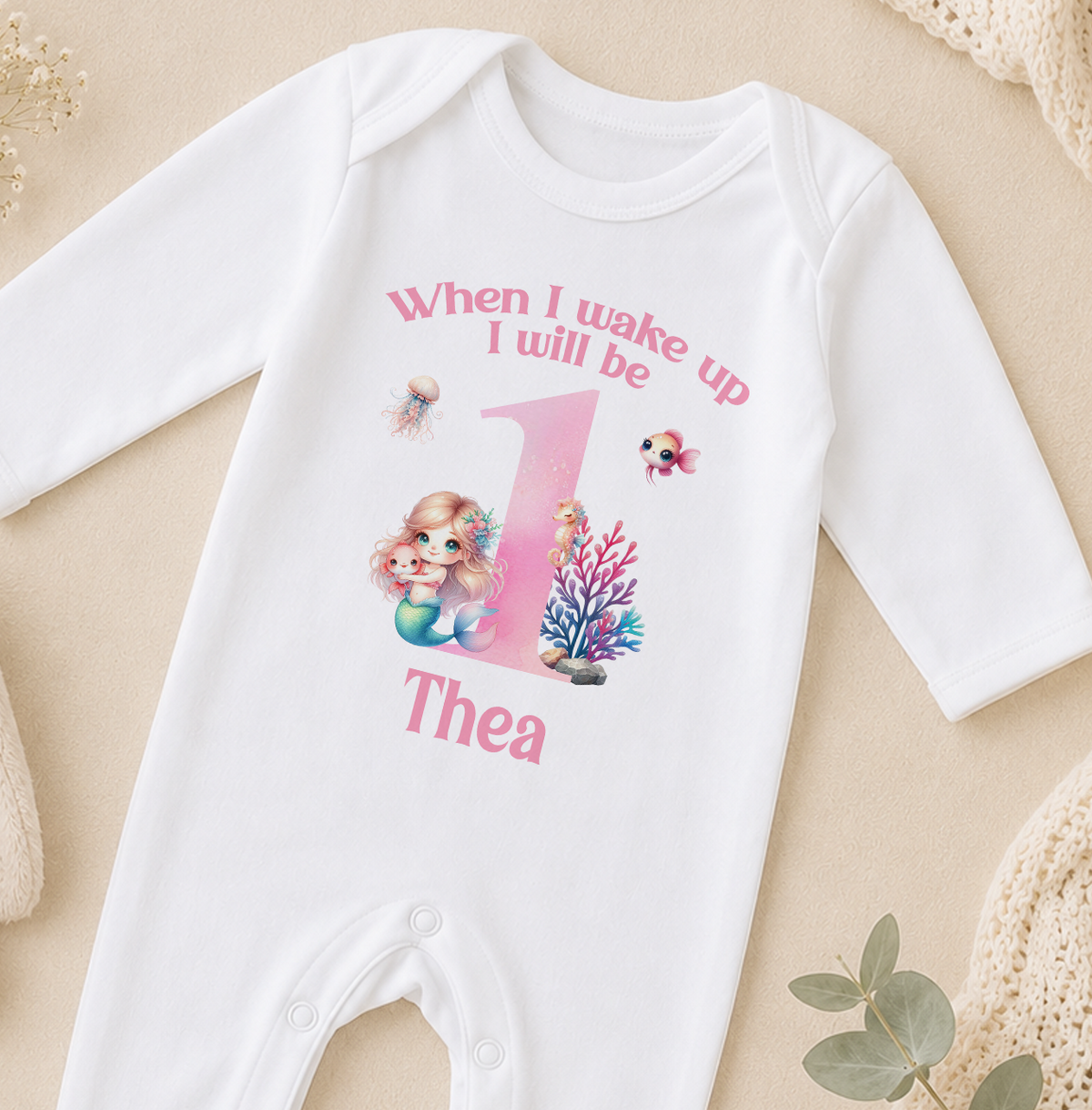 A white onesie with a mermaid design and the text "When I wake up I will be up" printed on it, along with the name "Thea" below the mermaid image.