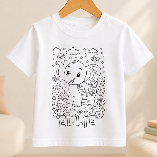 Line-art colour-in design of a baby elephant with a raised trunk, surrounded by butterflies, leaves and flowers, printed on a white kids' t-shirt with a personalised name below