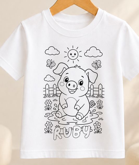 Colour-in kids t-shirt with a black-and-white line art pig in a farmyard scene, personalised with a name in bubble letters