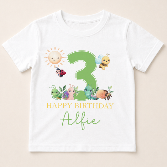 A white t-shirt with a graphic design featuring a large number 3 surrounded by various cartoon insects and animals, along with the text "Happy Birthday Alfie".