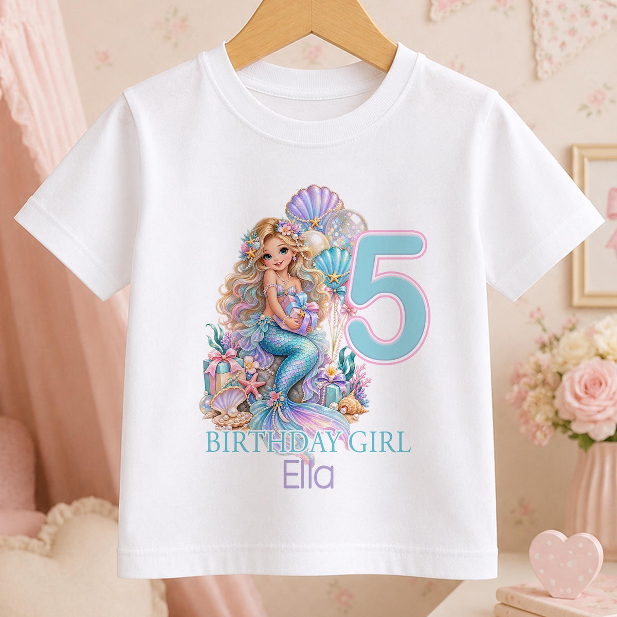White cotton t-shirt printed with a pastel mermaid among shells and coral beside a large age number, with Birthday Girl and a name below.