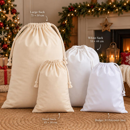 a collection of four white drawstring bags, each with different sizes, arranged on a wooden floor in front of a Christmas tree.