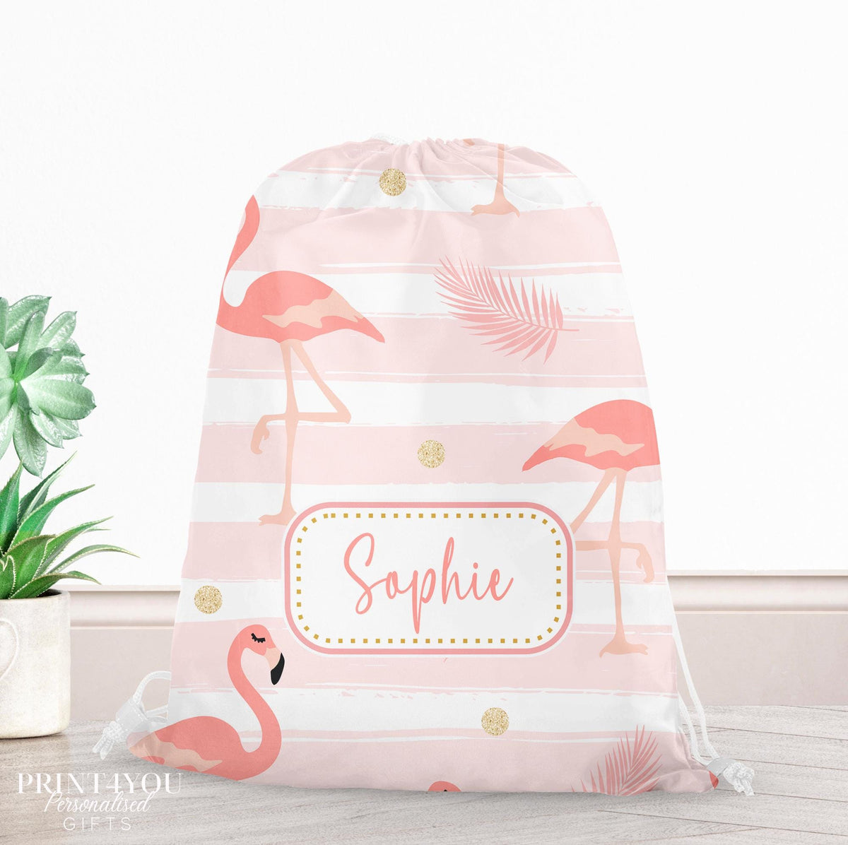 Pink drawstring PE bag printed with a flamingo, palm leaf and gold dot design, personalised with a child's name across the front