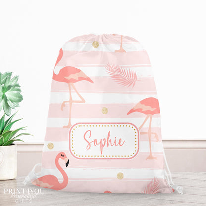 Pink drawstring PE bag printed with a flamingo, palm leaf and gold dot design, personalised with a child's name across the front