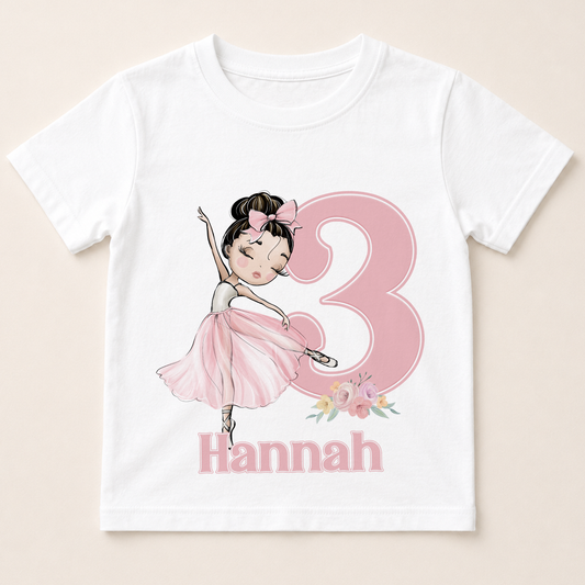 A white t-shirt with a pink illustration of a young girl in a ballerina pose and the number 3, along with the name "Hannah" below the number.
