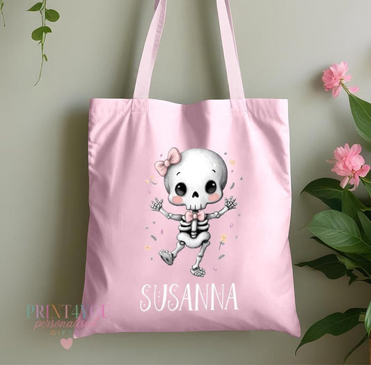 Personalised pink skeleton Halloween tote bag with a pink bow design and custom name, shown in pink