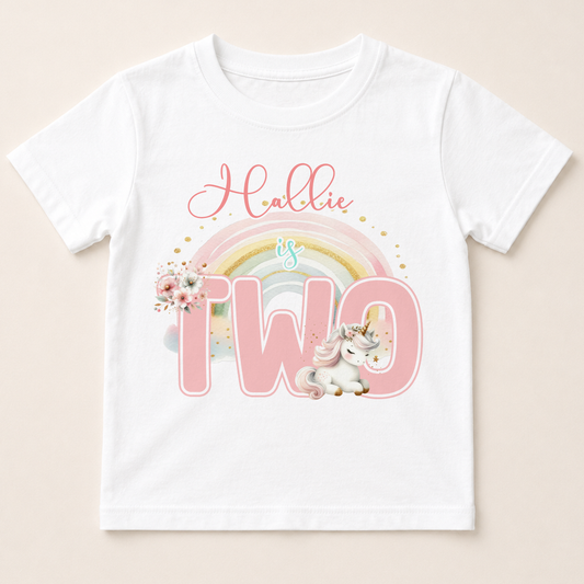 Personalised unicorn and rainbow birthday t-shirt printed with a child's name and age number.